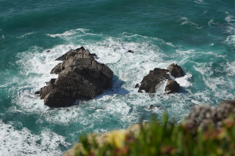 two rock outcrops next to the ocean on top of some water