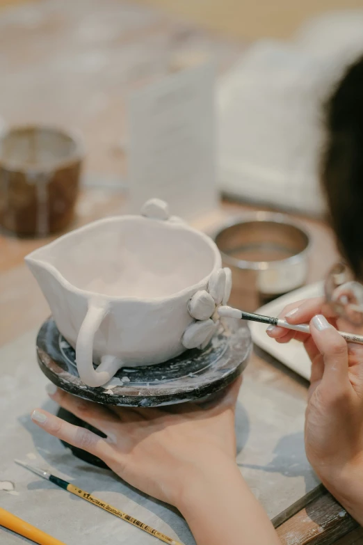 woman using white ceramics on plate to form cup