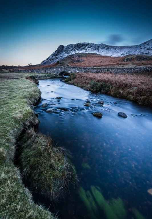 a small river running through a grass covered field