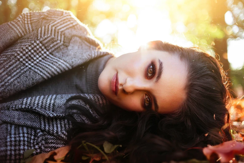 a woman laying in a field of leaves