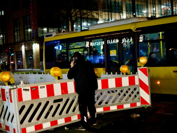 a man on the phone standing in front of a bus