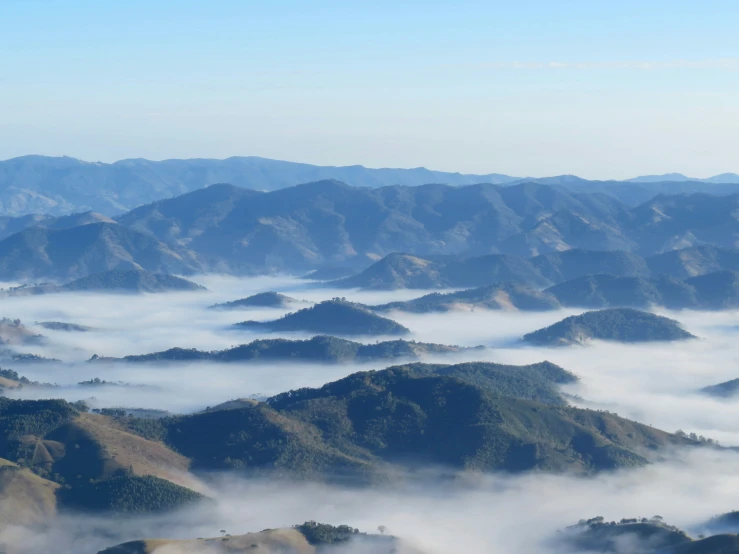 the top of many mountains with a blanket of clouds below