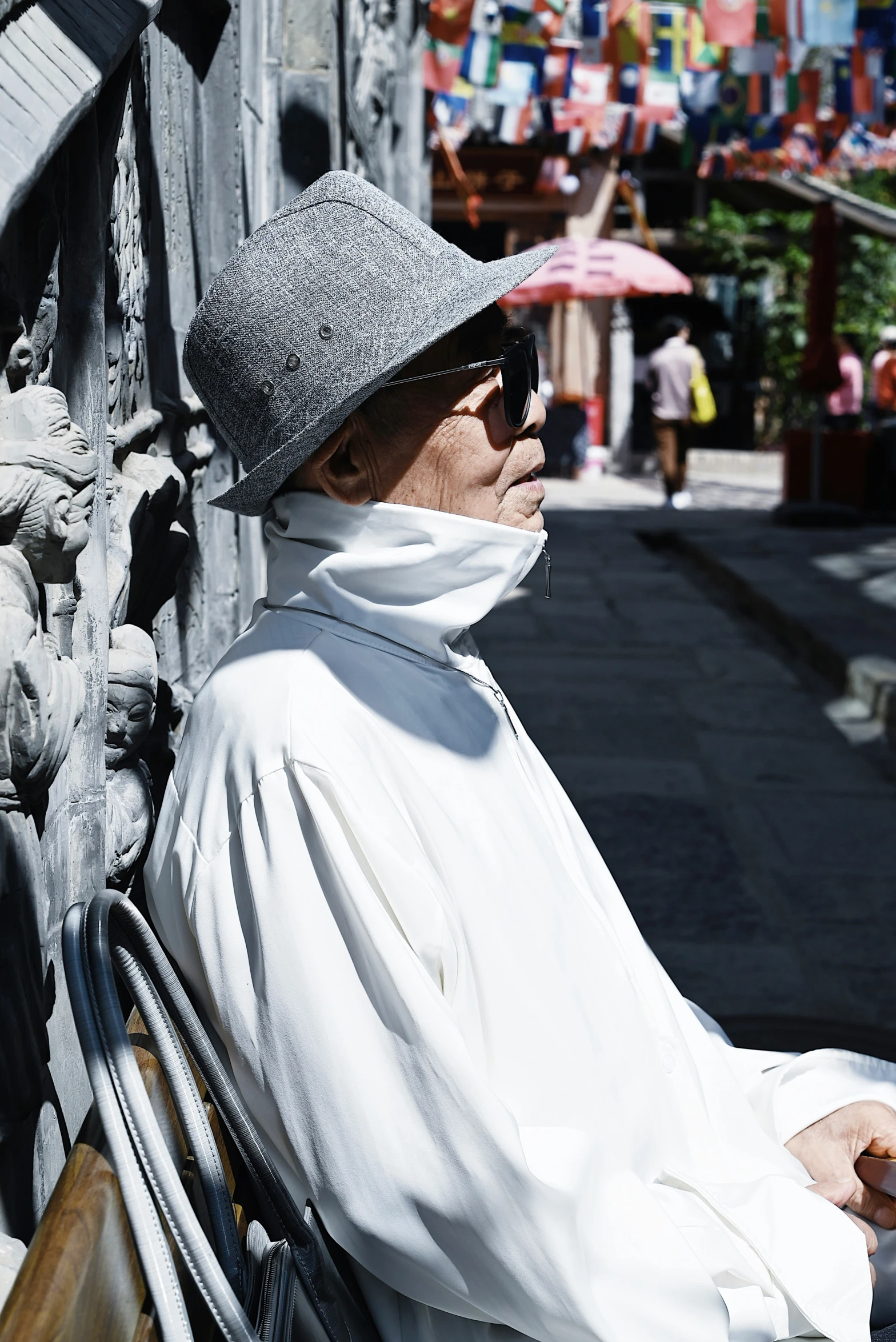 a woman sits on a bench wearing sunglasses and a hat