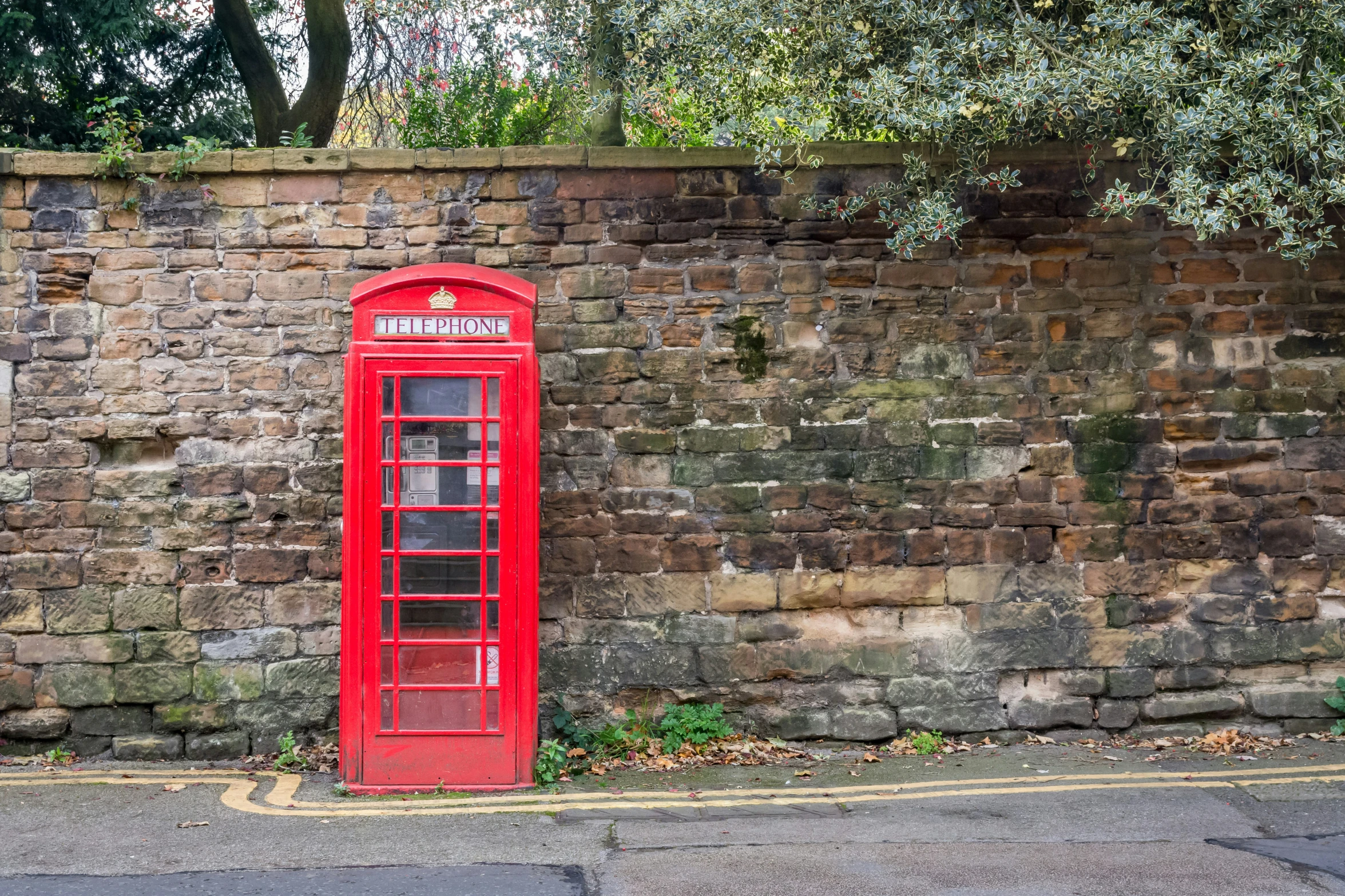 a red phone booth next to a brick wall