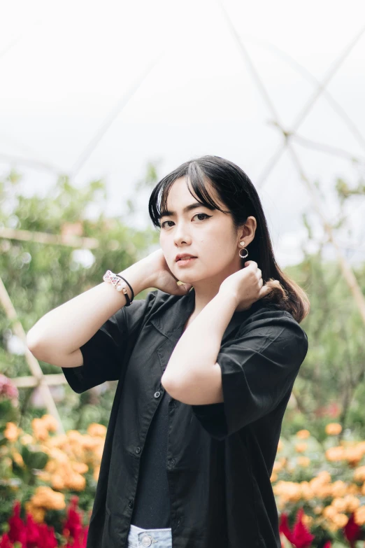 the woman is standing near a tree, wearing a black shirt