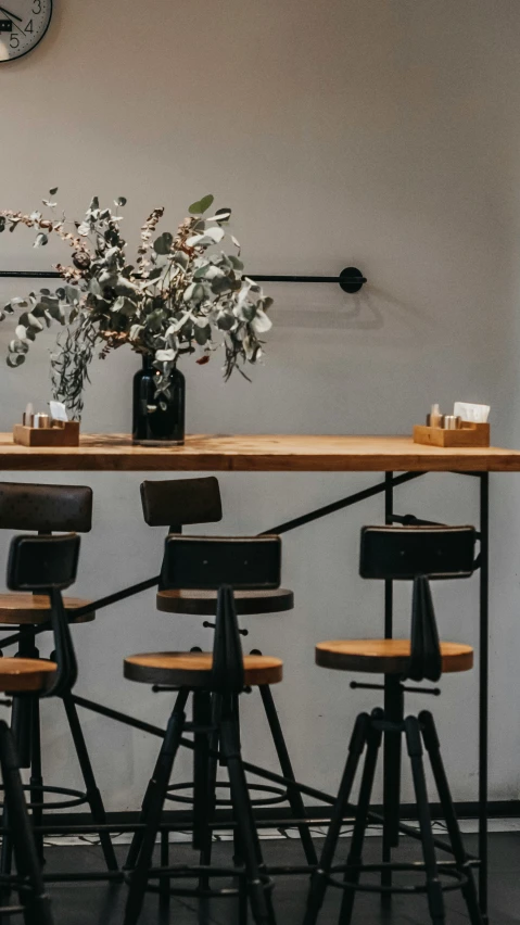 three stools and table with a vase and clock in a room