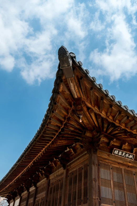 the top of a wooden pagoda structure under a partly cloudy blue sky