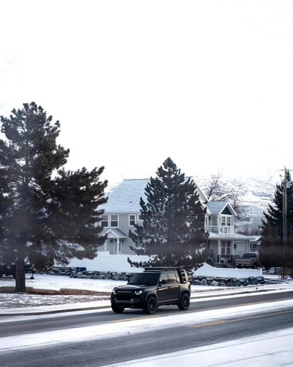 the suv is driving down the street as it snows