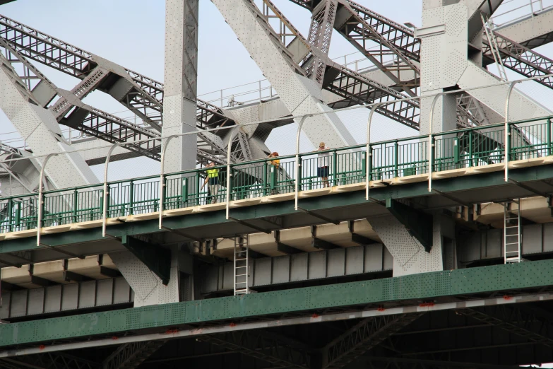 a man with green umbrella standing on top of bridge
