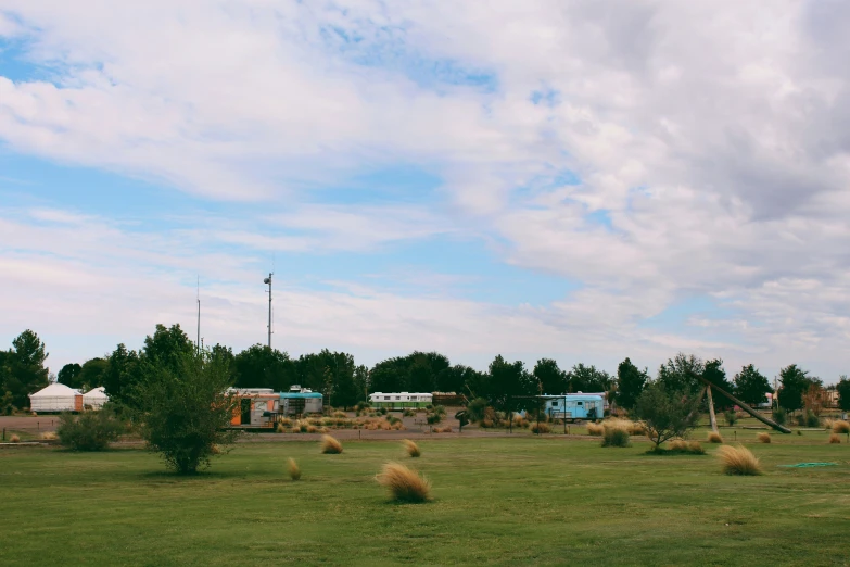 an empty field with a large structure and trees in the background