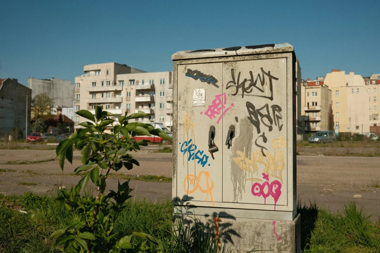 a small white cabinet in grass with other white buildings behind