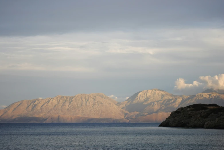 the view of a mountain range across water from a large island