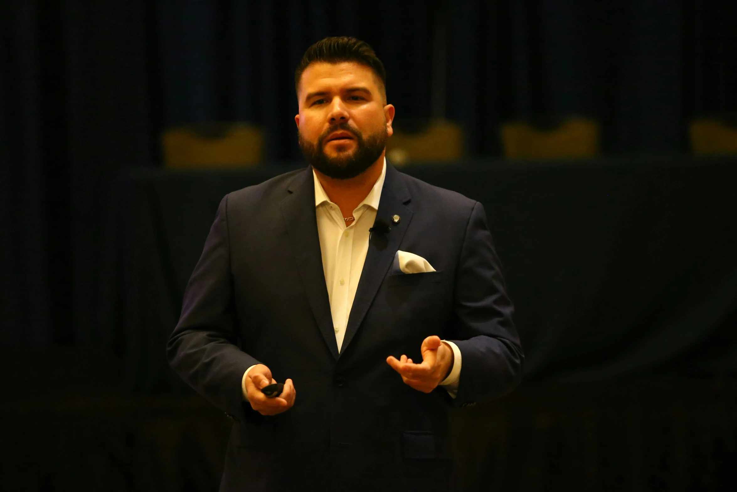 man in a suit standing in front of a stage