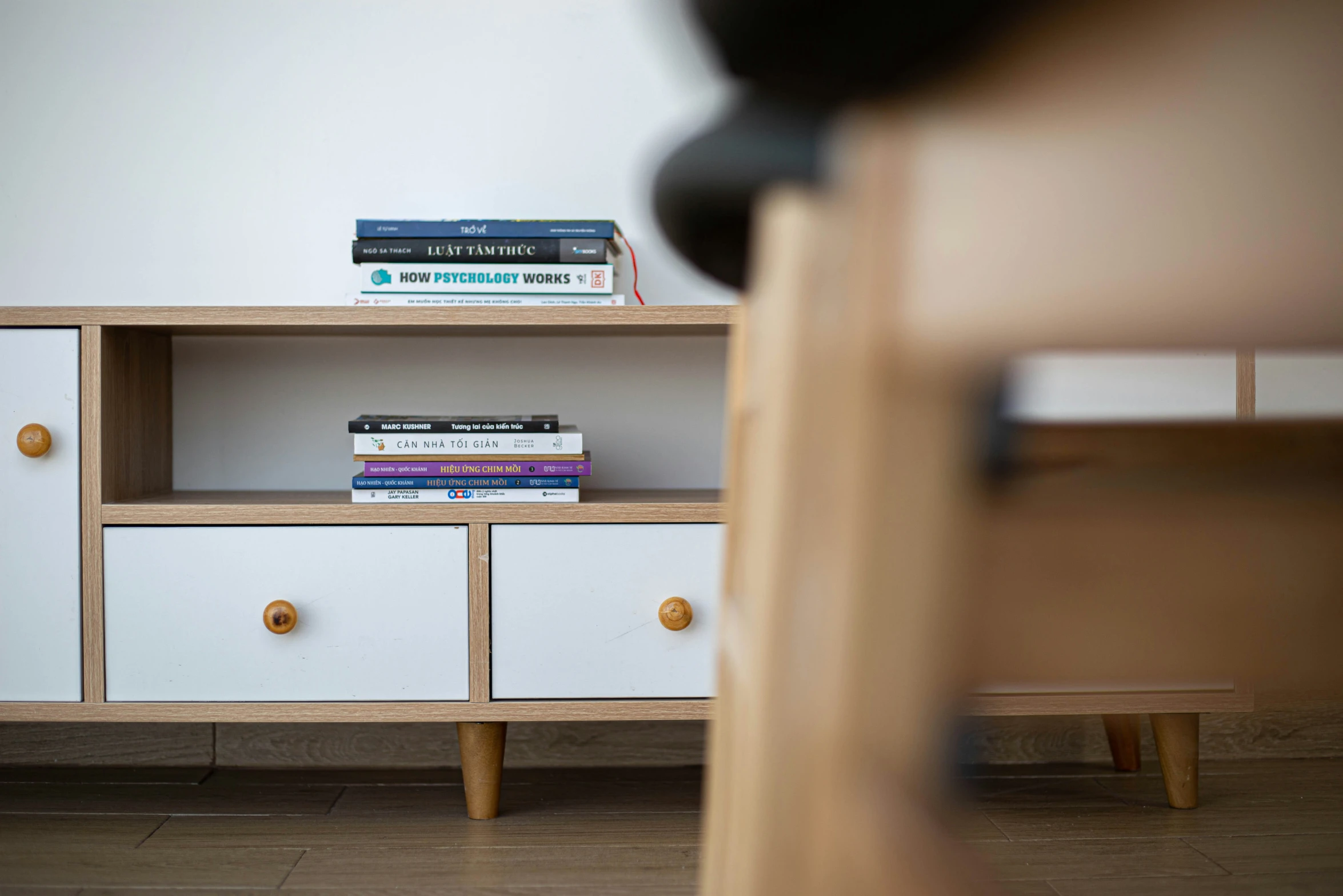 a white shelf topped with three books next to a chair