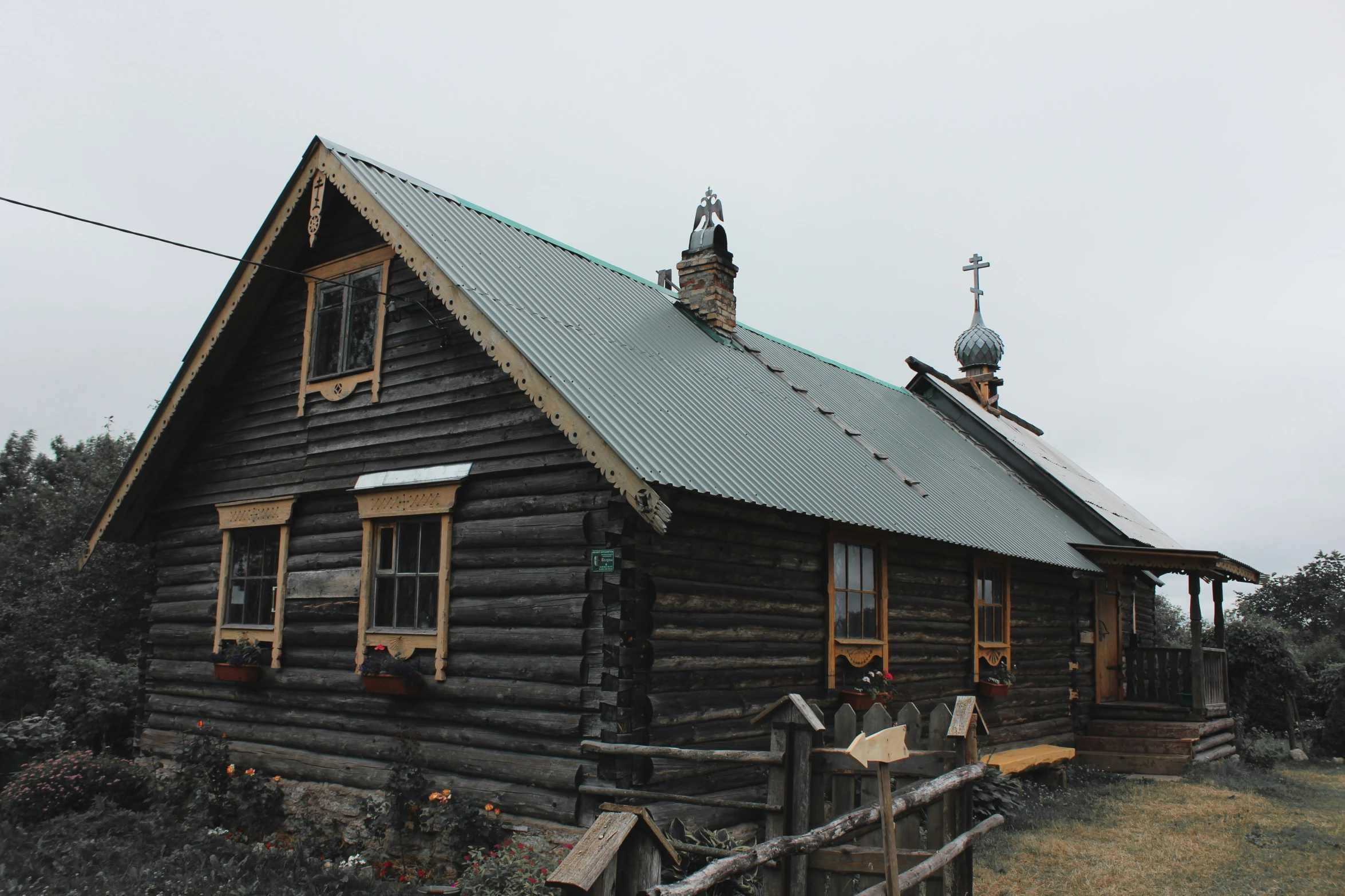 a small wooden house with a green roof and a large porch