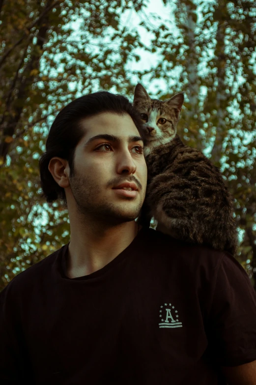 a man is holding his cat on his shoulder