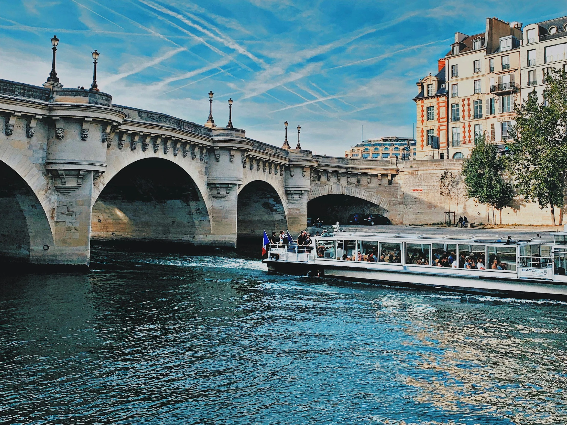 a white boat on river with bridge behind it