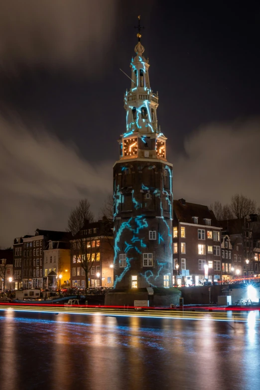 the illuminated clock tower sits in front of the dark city buildings