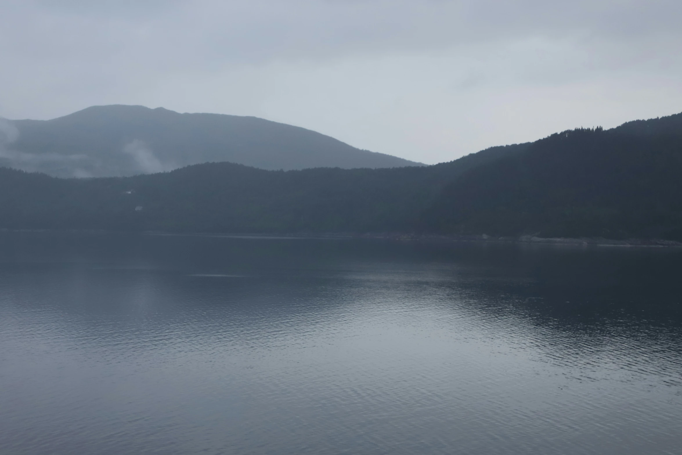 fog and dark water with green hills in the background