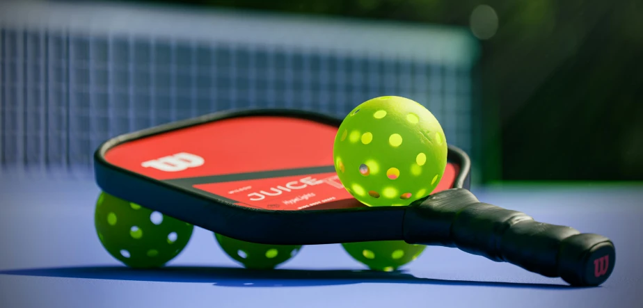 a green tennis ball and a racket are on the court