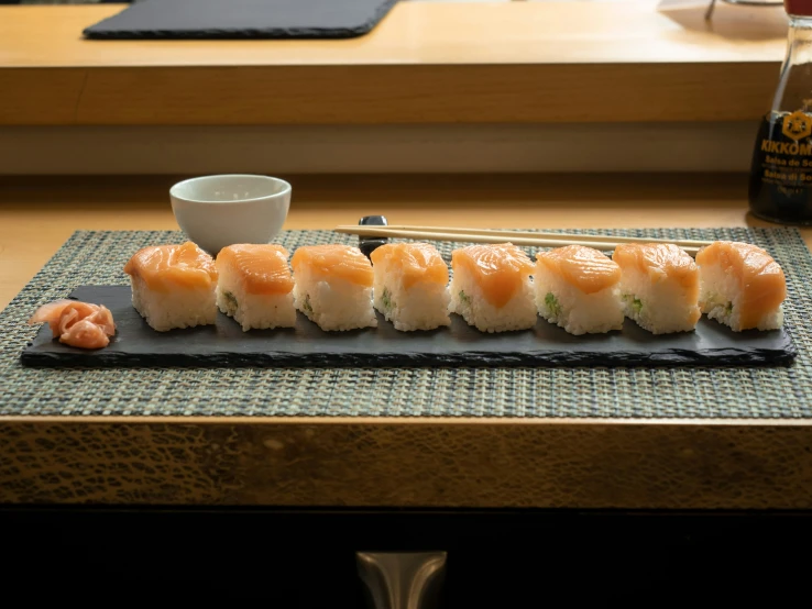 a variety of sushi on a plate and a small cup