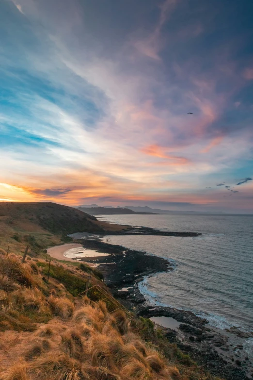 the view of a sunset from a hill overlooking the ocean