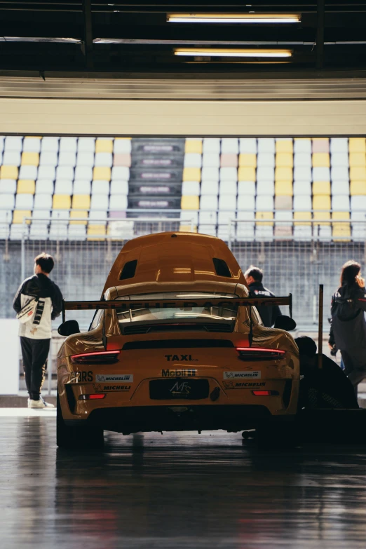 two people near a yellow car with the hood up