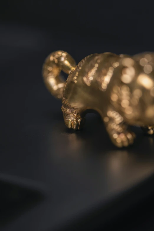 a small golden bear statue is on a black surface