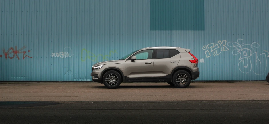 a silver car parked by a wall with graffiti