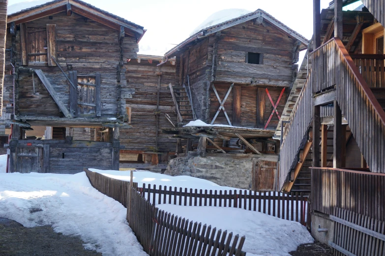 some old buildings with snow and a fence