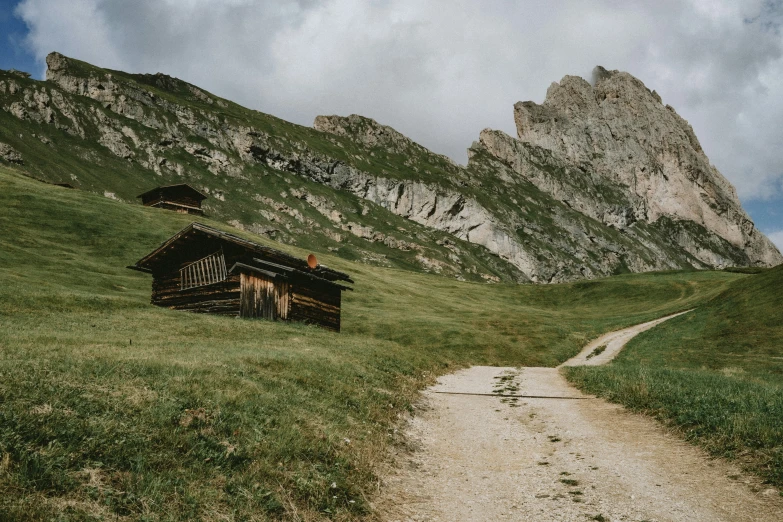 an old cabin sits on the side of a grassy hill