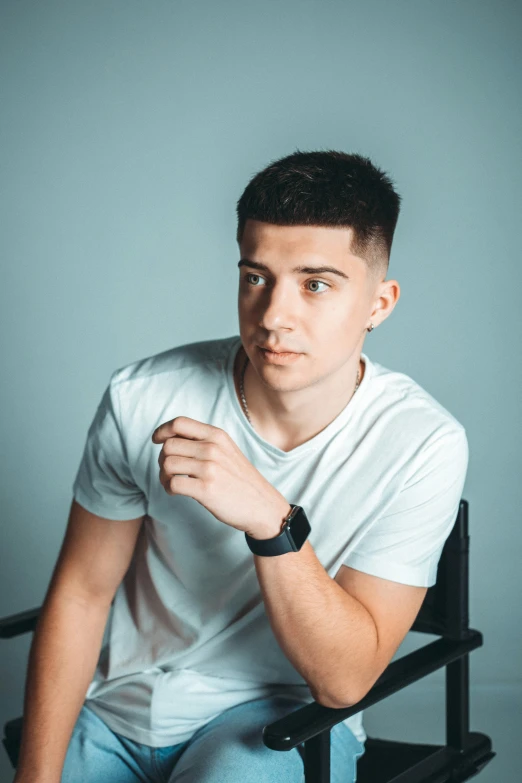 man in white shirt sitting on black chair holding his hand up