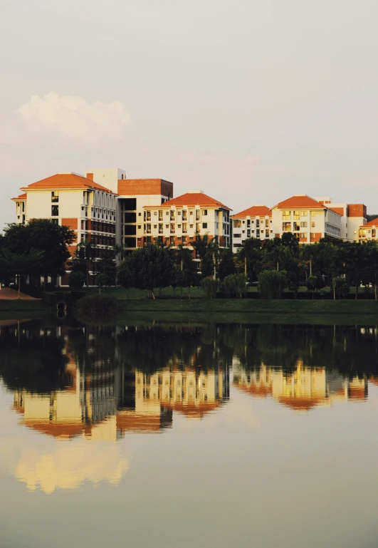 several buildings reflecting in the still water of a pond