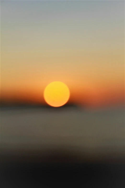 a blurry sunset view of the sun on the horizon