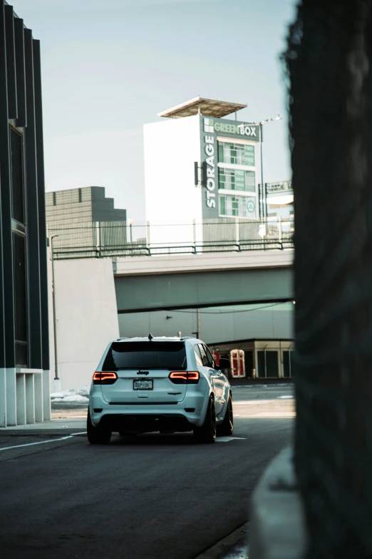 a white car drives down the road near tall buildings