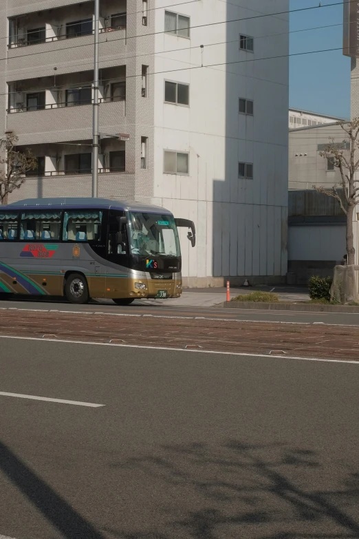 a silver and gold bus is sitting on the street