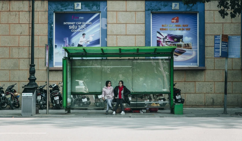 a couple of people sitting on a bench outside of a building