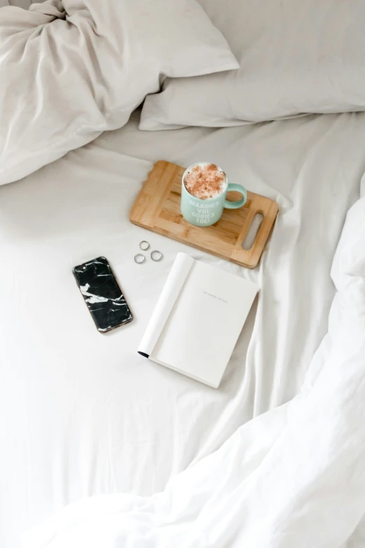 a cup of coffee sits on a table near an open book