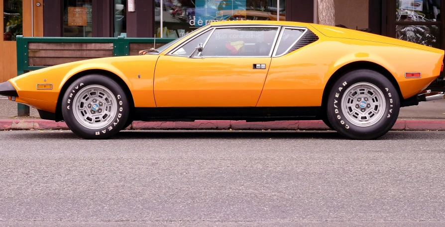 an orange sports car parked in front of a store