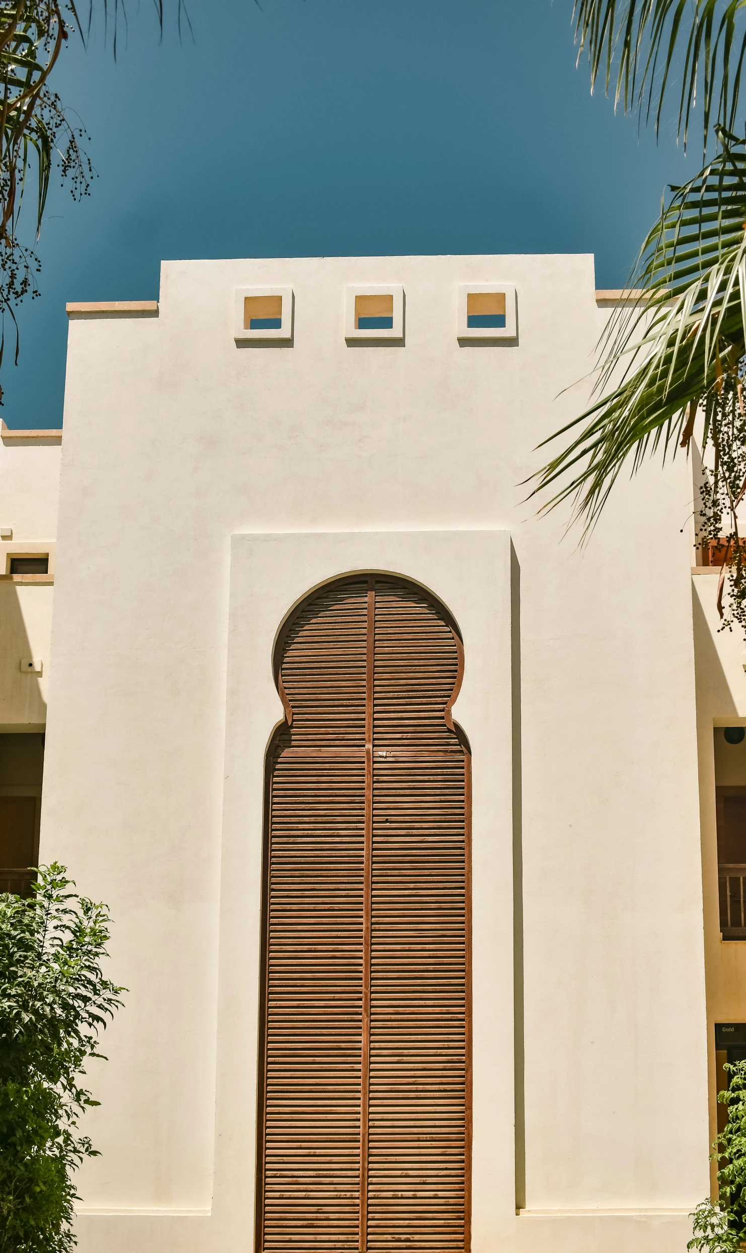 an arched wooden door and shutters on a white stucco building