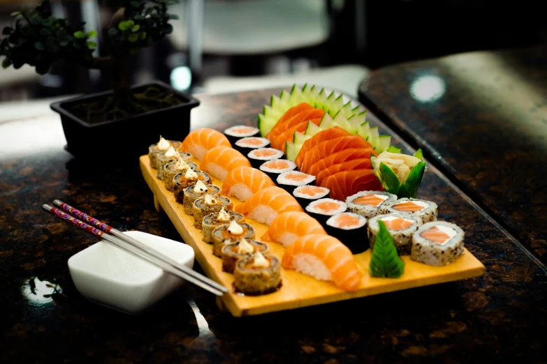 a wooden platter of sushi and other food on a table