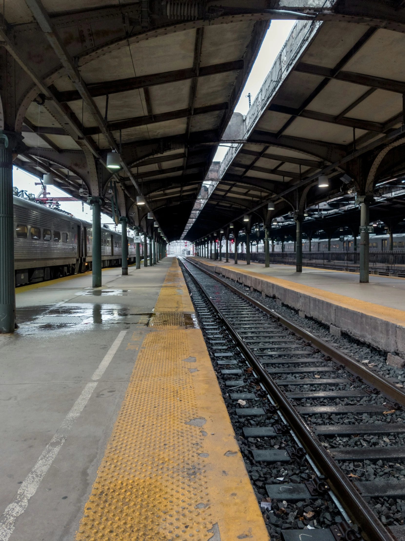 a train station with lots of tracks and one train pulling into it