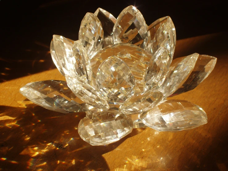 a crystal flower with leaves and stones on a wooden surface