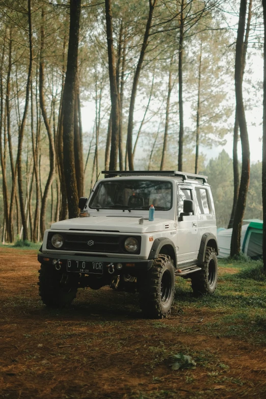 an off - road car parked near some trees in the forest