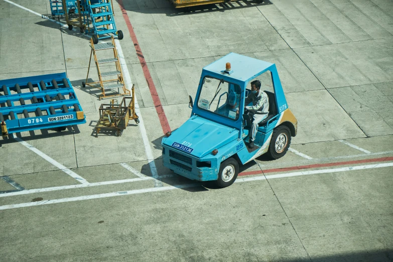 a man standing on top of a blue fork lift
