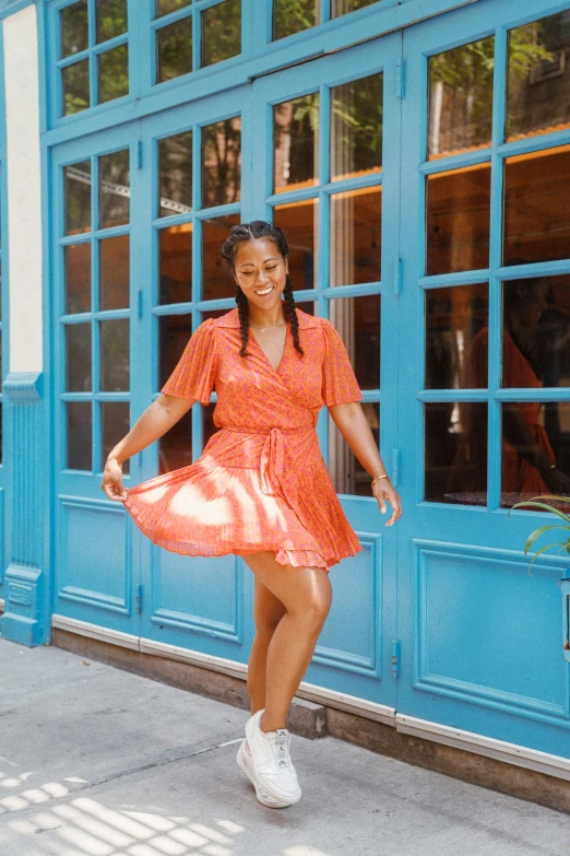 an african american girl in a dress smiles as she walks outside a building