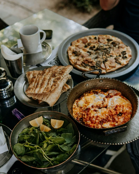 three pans and food are on a table near cups