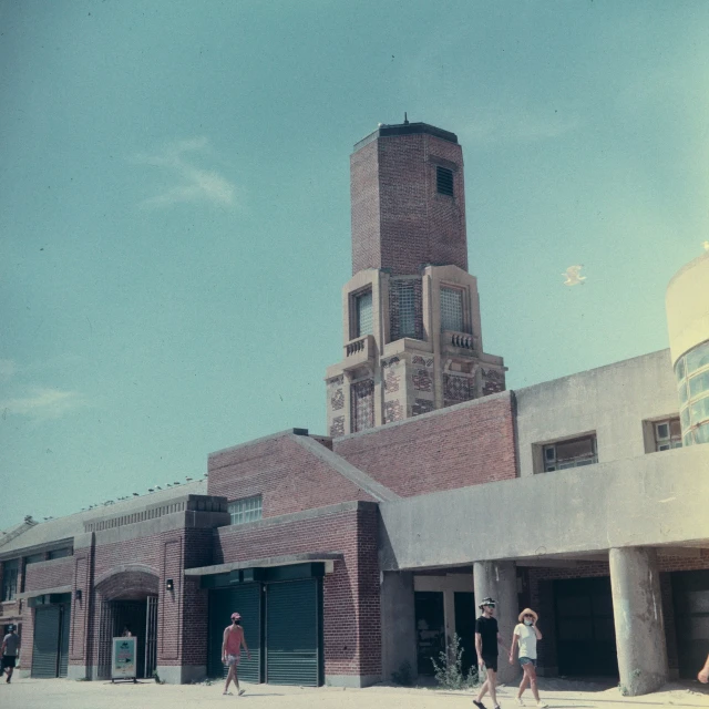 three people are walking past a building in a blue sky