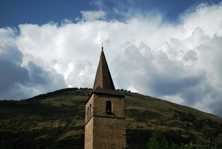 a brown church steeple under cloudy skies