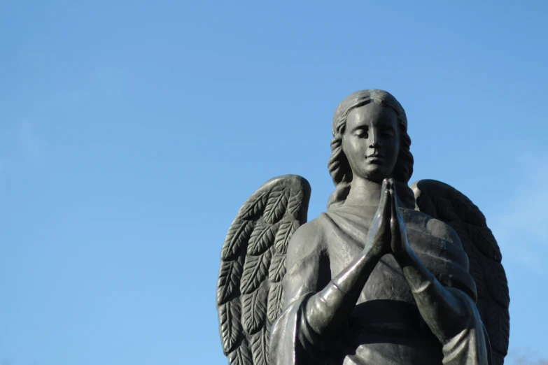 the statue shows the praying angel holding a cross